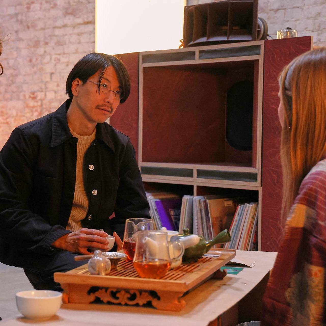 Conversation over a tea board beside a wooden sound system